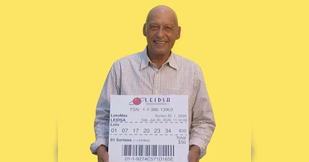 Smiling man in a checkered shirt holds a large lottery ticket against a bright yellow background.