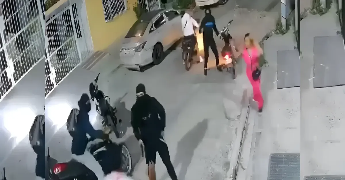 Nighttime street scene with masked individuals gathered near parked motorcycles and a car on the curb, a person in a bright pink outfit walking by. (Surveillance photo)