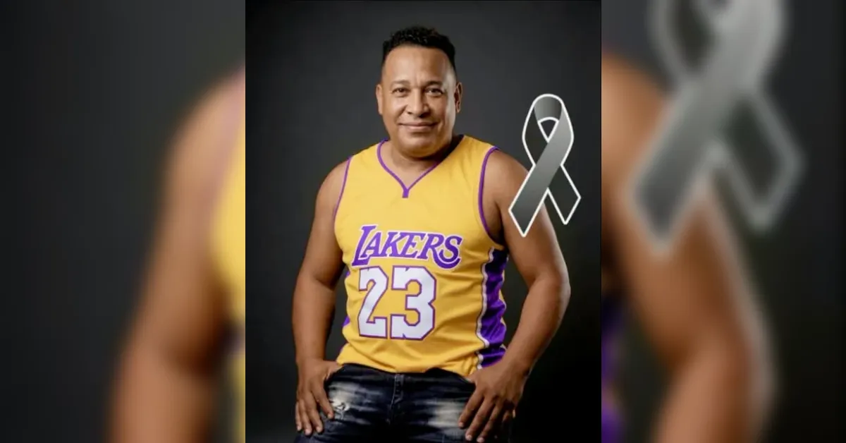 Man in a yellow Lakers jersey #23 poses with hands on hips against a dark background, a gray awareness ribbon on his right side.