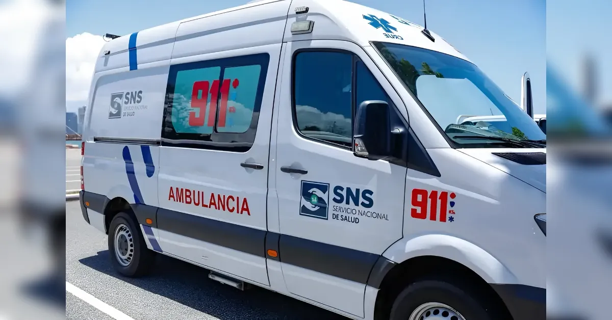 White ambulance van with 911 decals and SNS logo, labeled Ambulancia, parked on a sunny road outside a hospital area