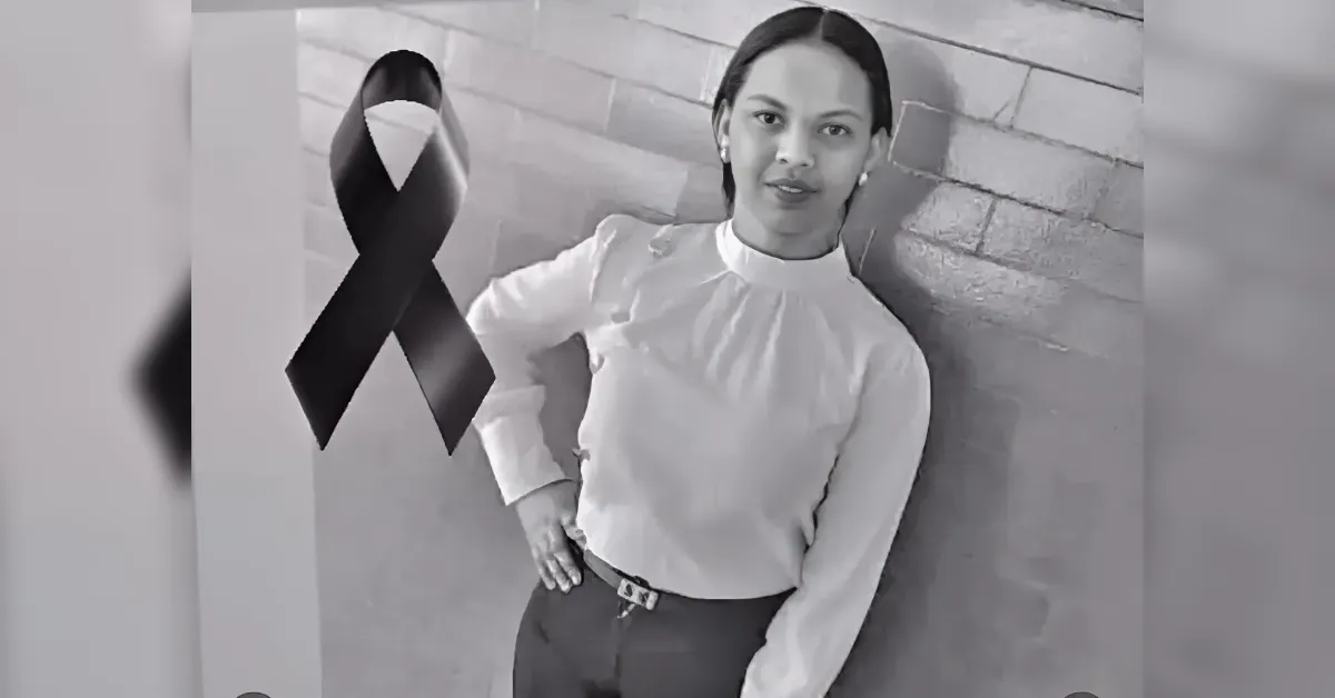 Grayscale photo of a woman in a white blouse standing against a brick wall, with a large black awareness ribbon in the foreground.