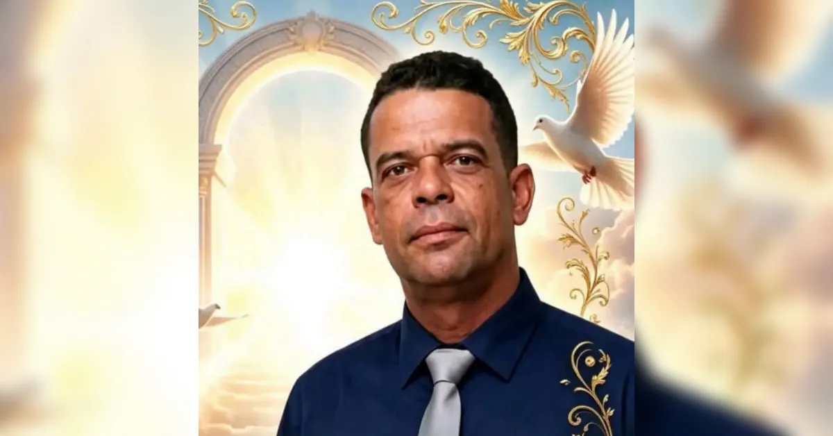 Portrait of a man in a dark blue shirt and light gray tie, standing before an ornate, heavenly backdrop with arches, gold scrollwork, and a white dove in the background.