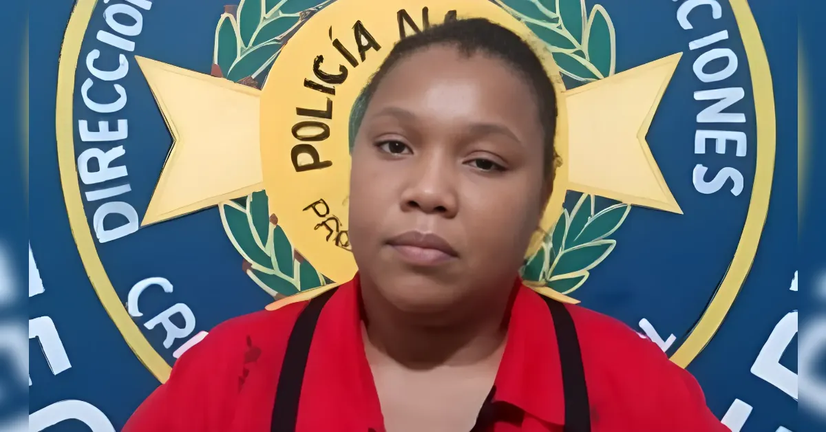 Woman in a red shirt with black straps sits in front of a blue wall featuring a large police emblem (Policía Nacional) in the background.