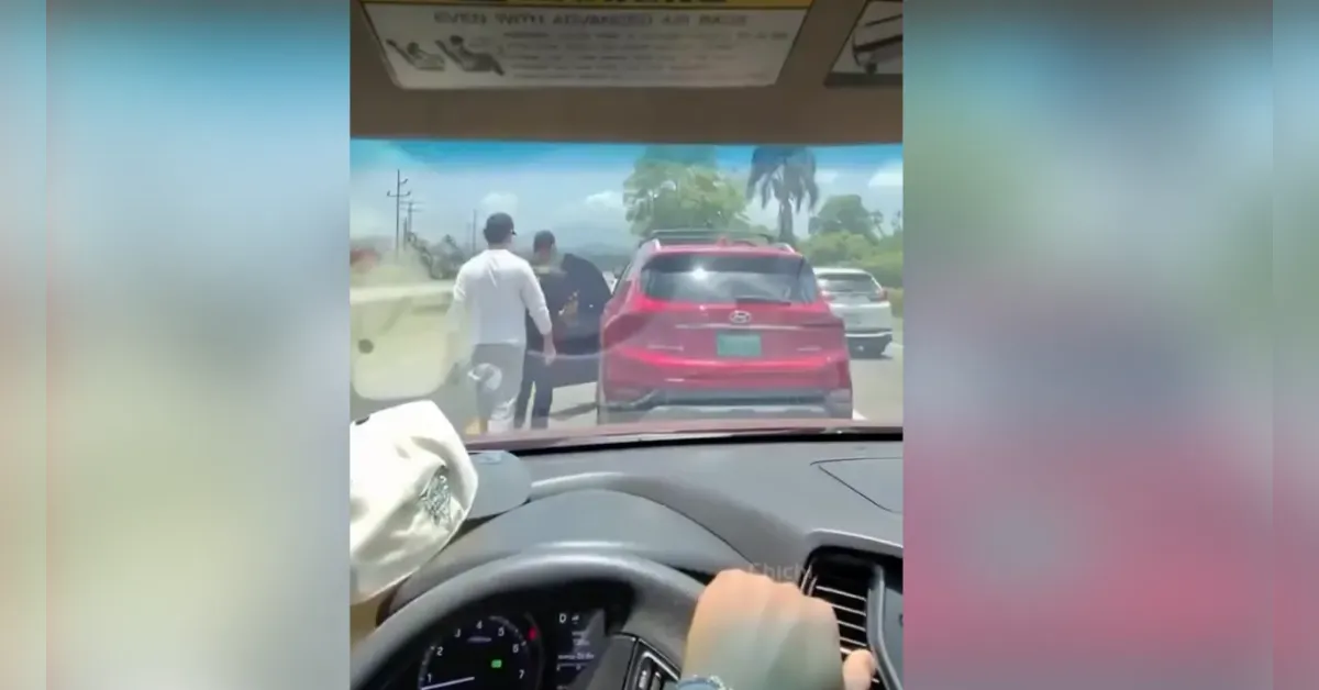 Dashcam view from inside a car: a red SUV is stopped on a sunny road with two men standing by the driver’s door as another car waits behind.