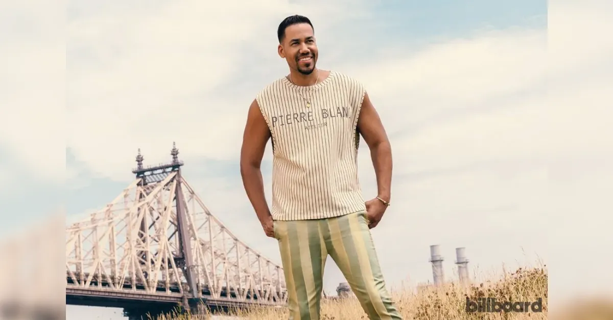 Man posing outdoors in a sleeveless striped shirt and striped pants, with a bridge in the background and a Billboard logo in the corner.