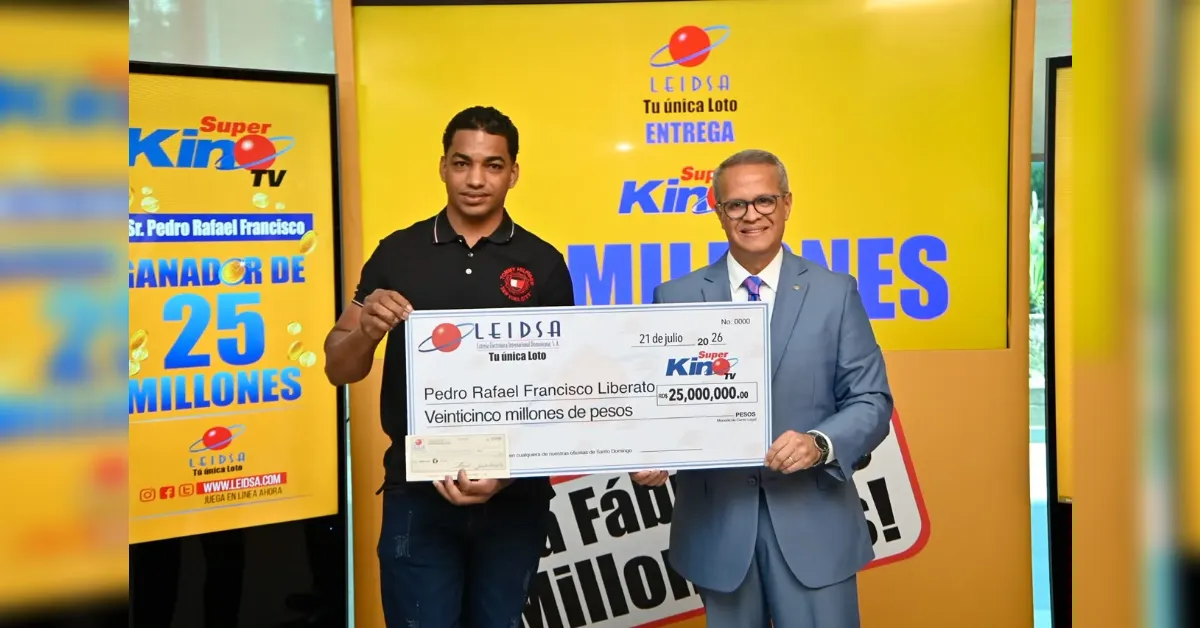 Two men stand in front of a bright yellow backdrop, holding a large ceremonial check for 25,000,000 pesos from LEIDSA/Super Kin TV. Typical prize presentation scene.