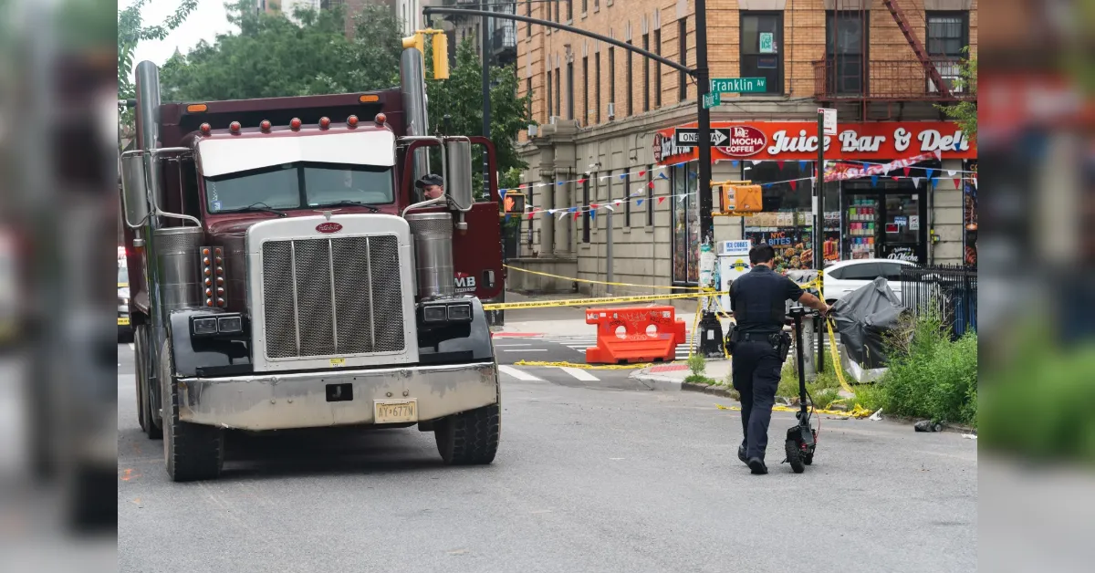 Large red truck blocks a city street; a police officer with a scooter and yellow caution tape nearby.
