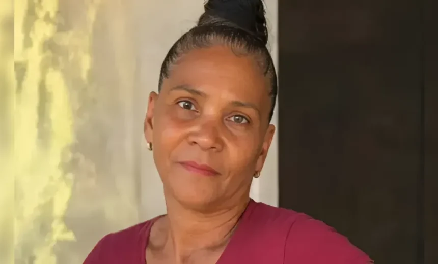 Portrait of a smiling woman with a high bun, wearing a maroon top.
