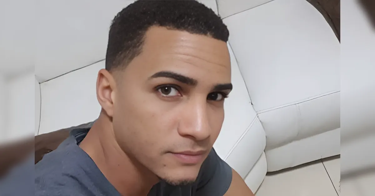 Close-up of a young man with short dark hair on a light-colored sofa, looking at the camera.