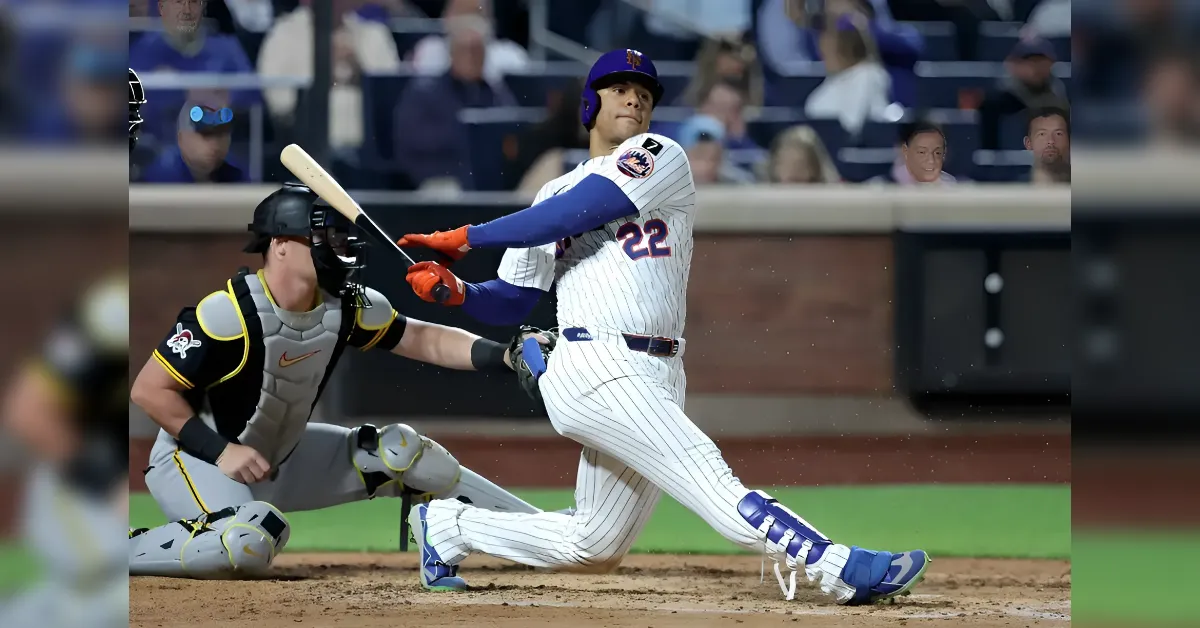 Baseball batter in a white pinstripe uniform swings at a pitch near home plate as the catcher in black and yellow crouches behind him.