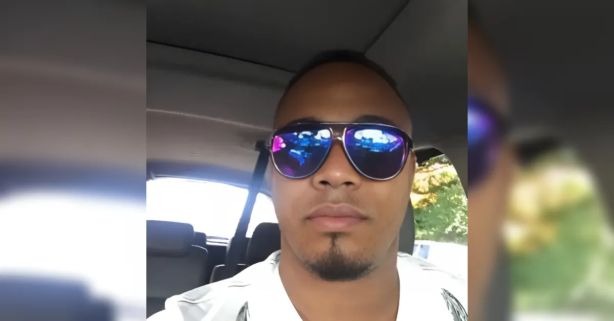 Man wearing blue mirrored sunglasses in the driver's seat of a car.