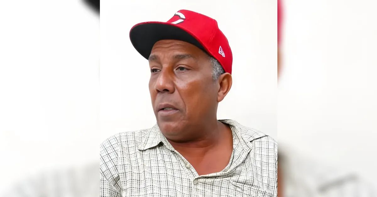 Man in a red baseball cap and light plaid shirt, looking to the left.