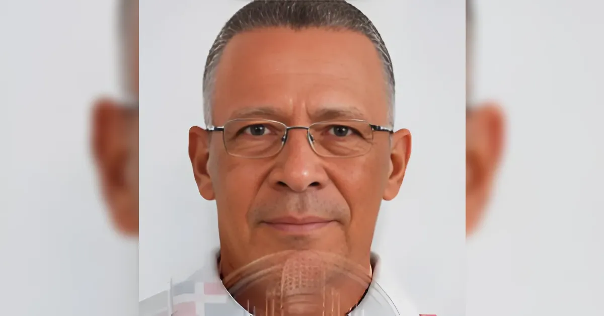 Close-up portrait of a middle-aged man wearing glasses with short gray hair against a light background.