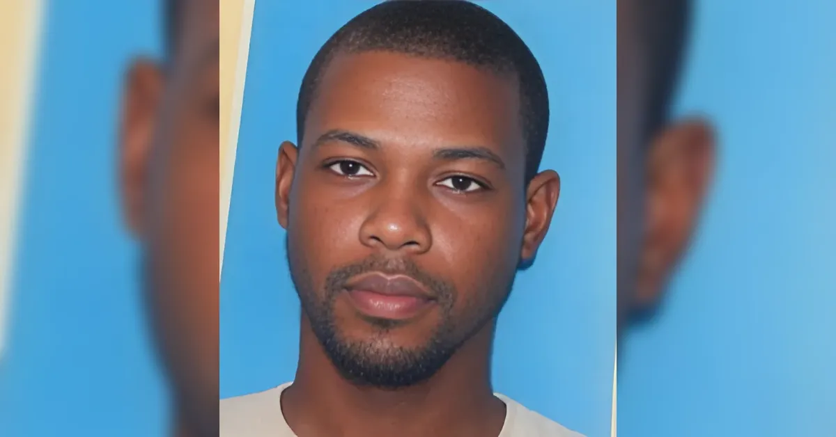 Portrait of a young man with short hair and light facial hair against a blue background, looking at the camera.