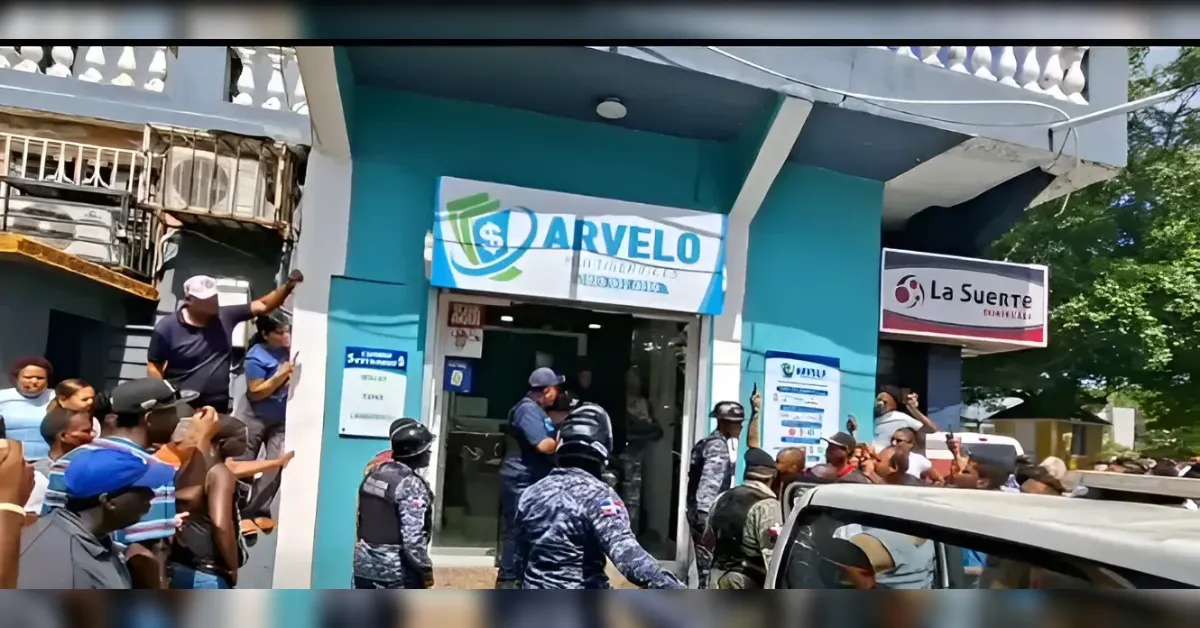 A crowd of people gathered outside a teal storefront with a blue-and-white sign above the entrance, while security guards in uniform stand near the doorway.