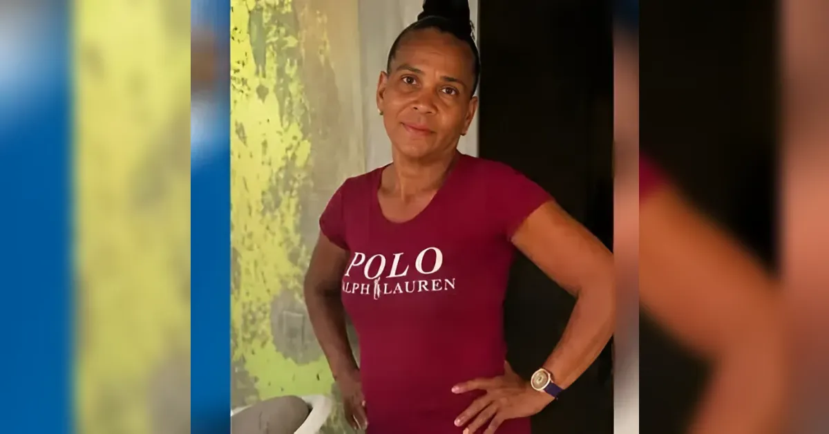 Woman with hands on hips, wearing a maroon Polo Ralph Lauren T-shirt, standing against a colorful wall.