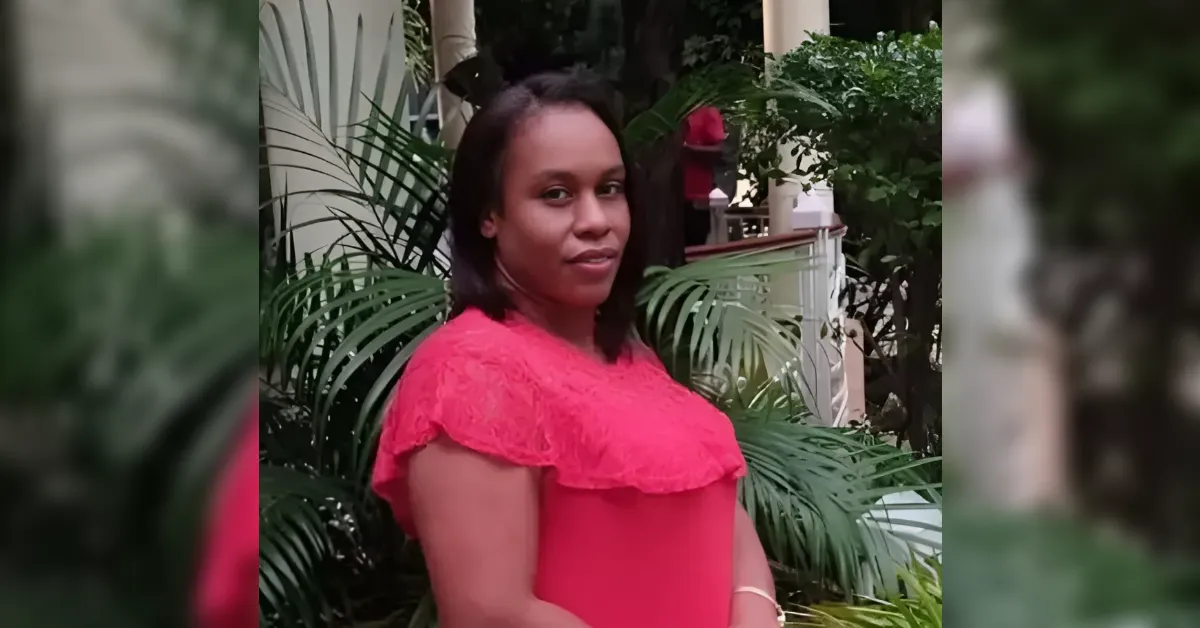 A woman in a bright pink lace top standing in a lush garden, looking over her shoulder at the camera.