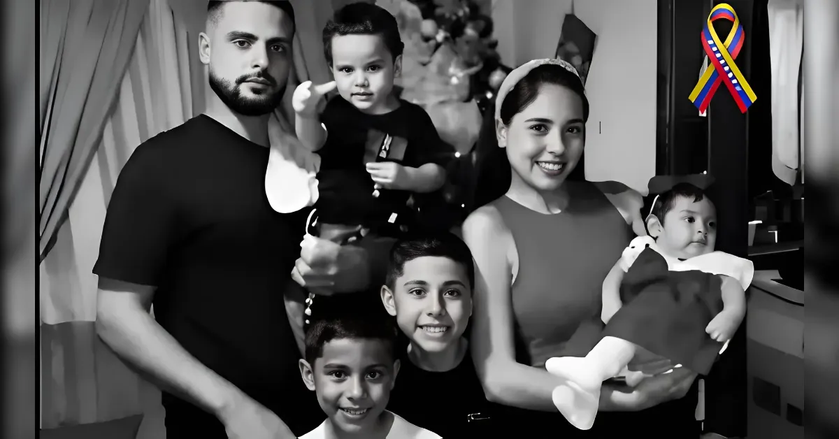 Family group portrait at home: father, mother holding baby, and three smiling children gathered together.