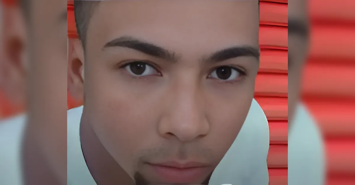 Close-up of a young man's face looking at the camera, with a red striped background.