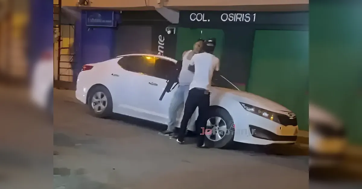 Two men argue beside a white sedan on a dim street, standing near the driver's side with the car mid-accident scene.