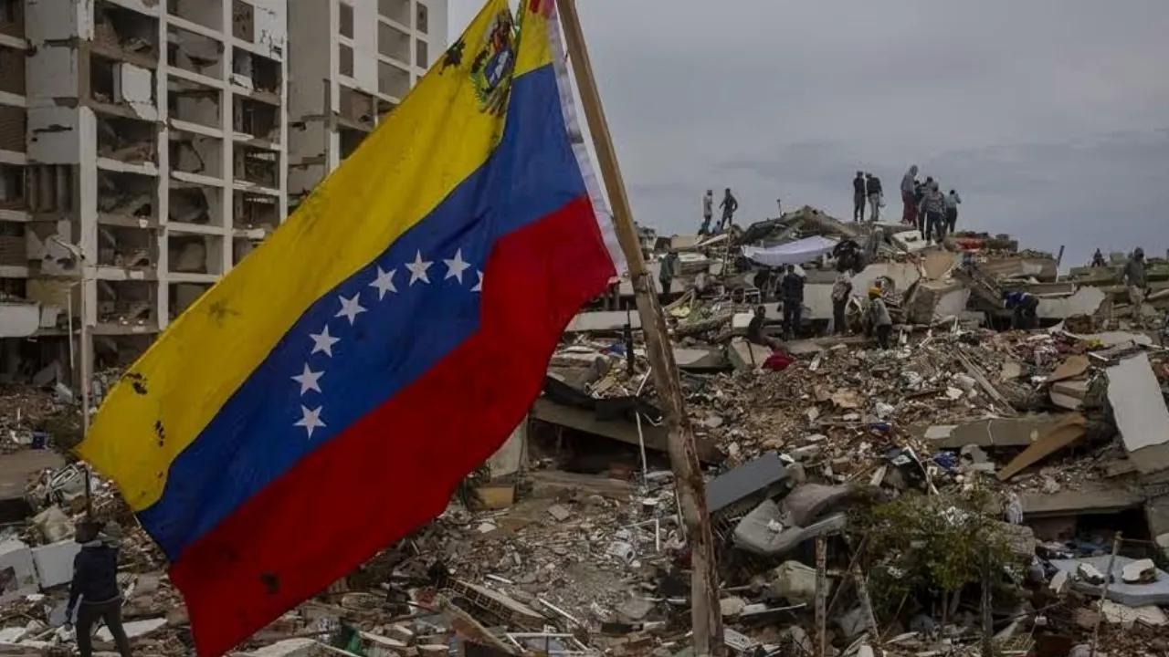 Venezuelan flag waving amid rubble from a collapsed building, with rescue workers in the distance.