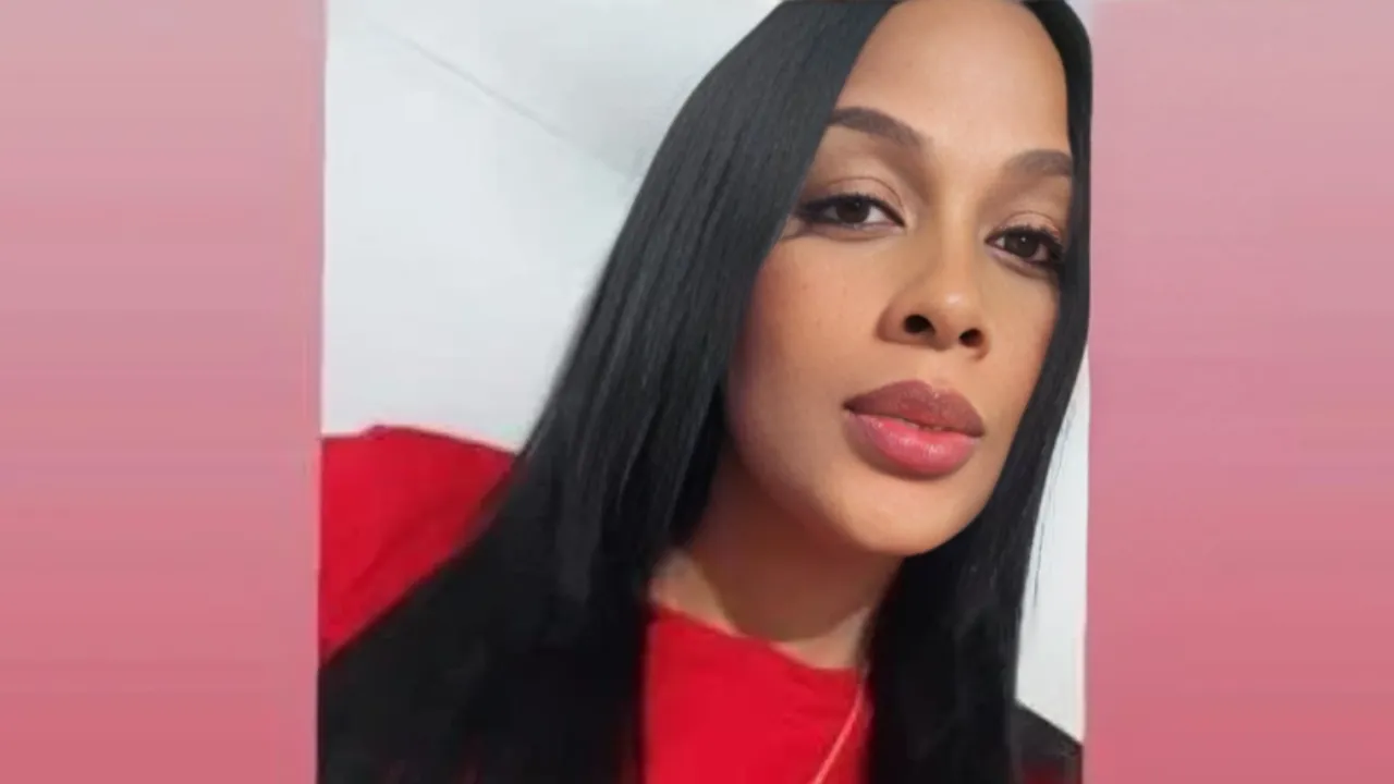 Close-up of a woman with long black hair wearing a red top, looking at the camera with neutral expression against a pink background.