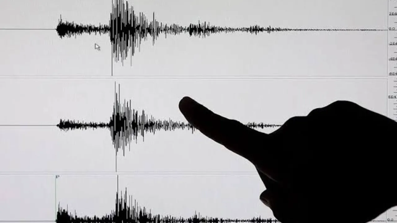 Person's hand points at a waveform on an audio editing screen, highlighting a spike in the audio track.