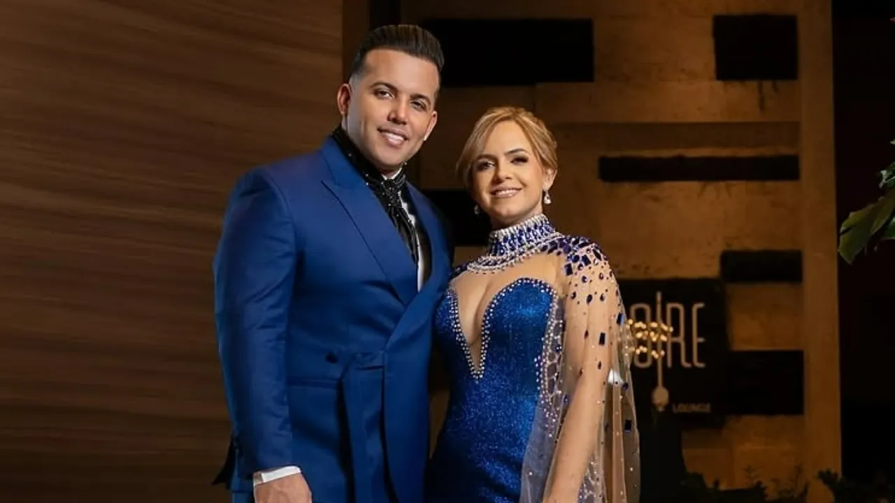 A man in a royal blue suit and a woman in a blue beaded gown pose together at a formal event.