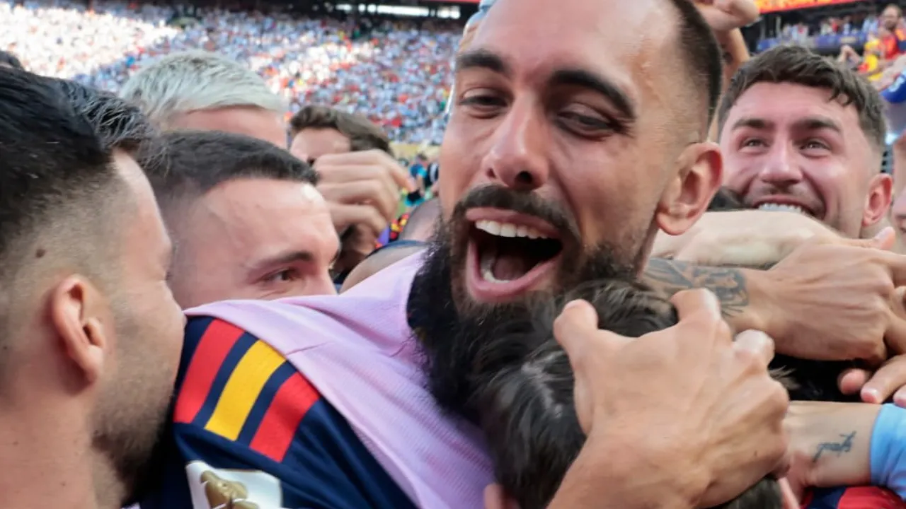 A group of teammates in a stadium celebrating, hugging and smiling after a match.