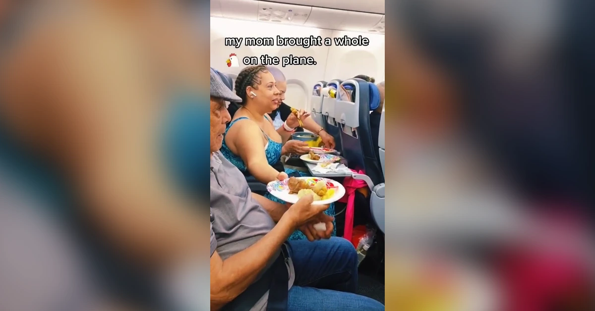 On a plane, a woman in a blue top eats from a plate while an older man beside her holds his own plate; caption reads 'my mom brought a whole chicken on the plane.'