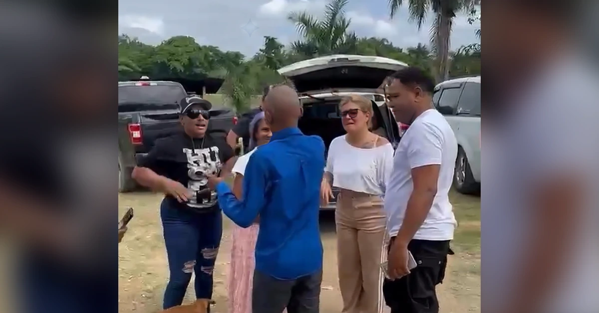 Group of five adults standing around an SUV with its trunk open, engaged in conversation outdoors.