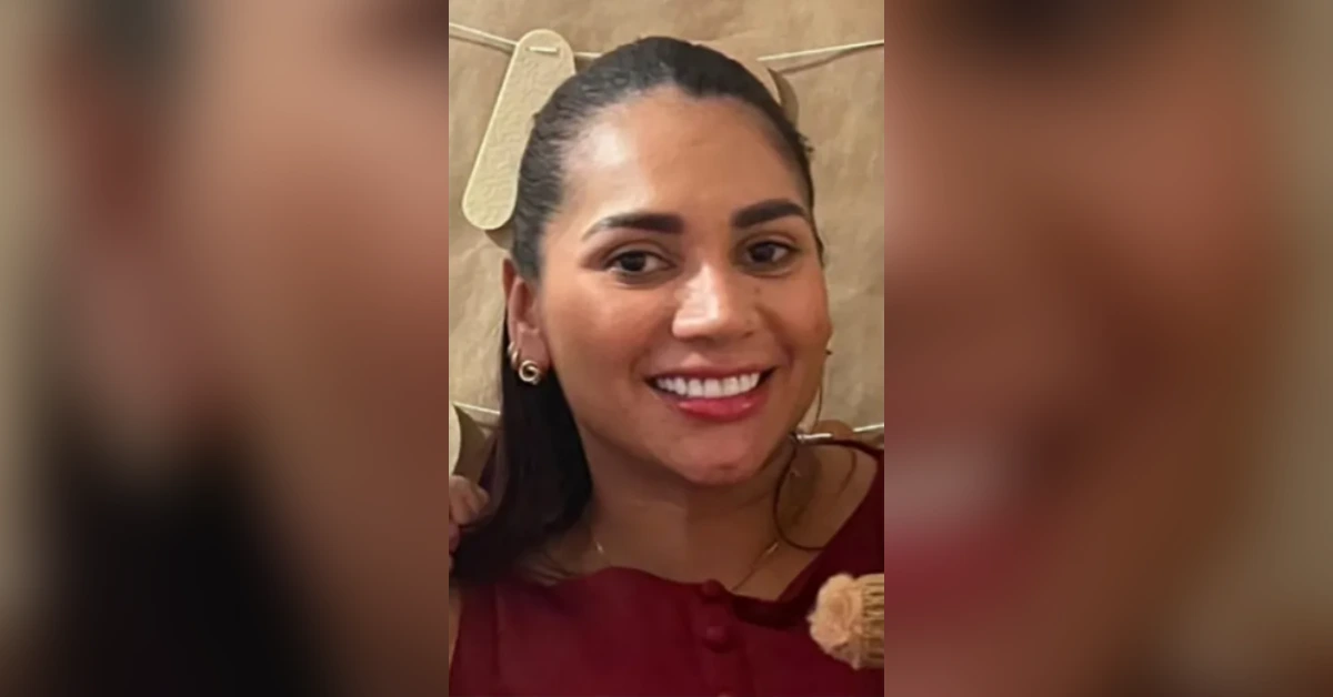 Smiling woman with dark hair pulled back, wearing a maroon top and gold earrings.