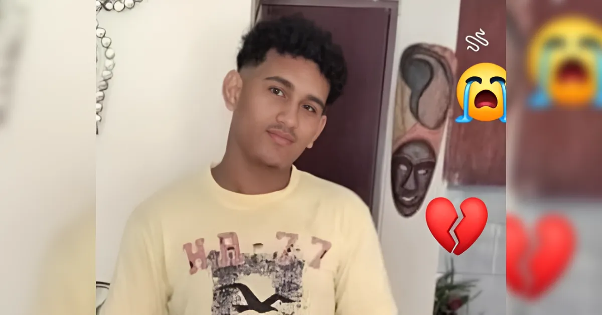 Portrait of a young man in a pale yellow T-shirt posing indoors, with heartbreak and crying emojis overlaid on the right side.