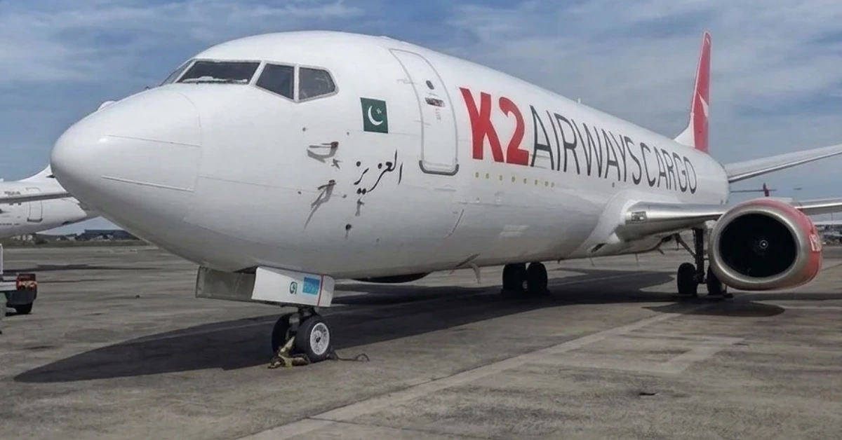 Front-left view of a white X2 Airways Cargo jet parked on the tarmac, nose in focus with the Pakistan flag on the fuselage.