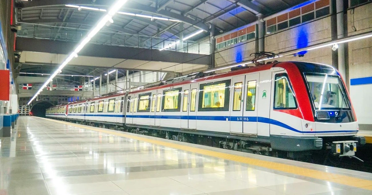 Modern automated metro train on an underground platform with a red front and blue stripe, doors closed, fluorescent lighting bright above, empty platform with tactile yellow edge line