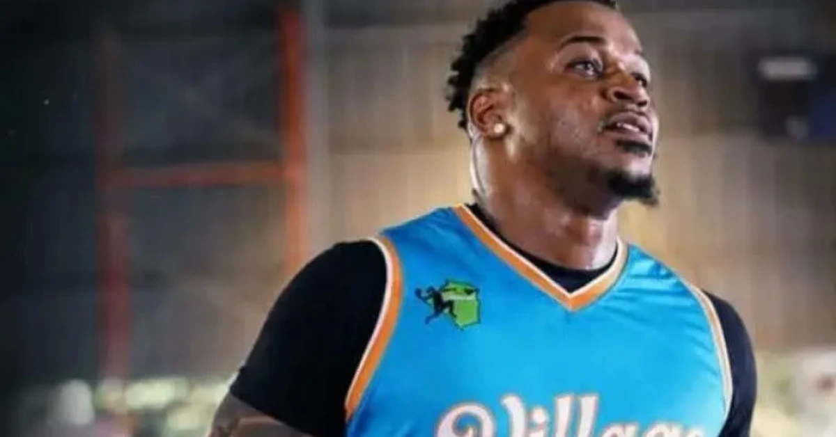Male basketball player in a blue jersey looks upward in a gym.