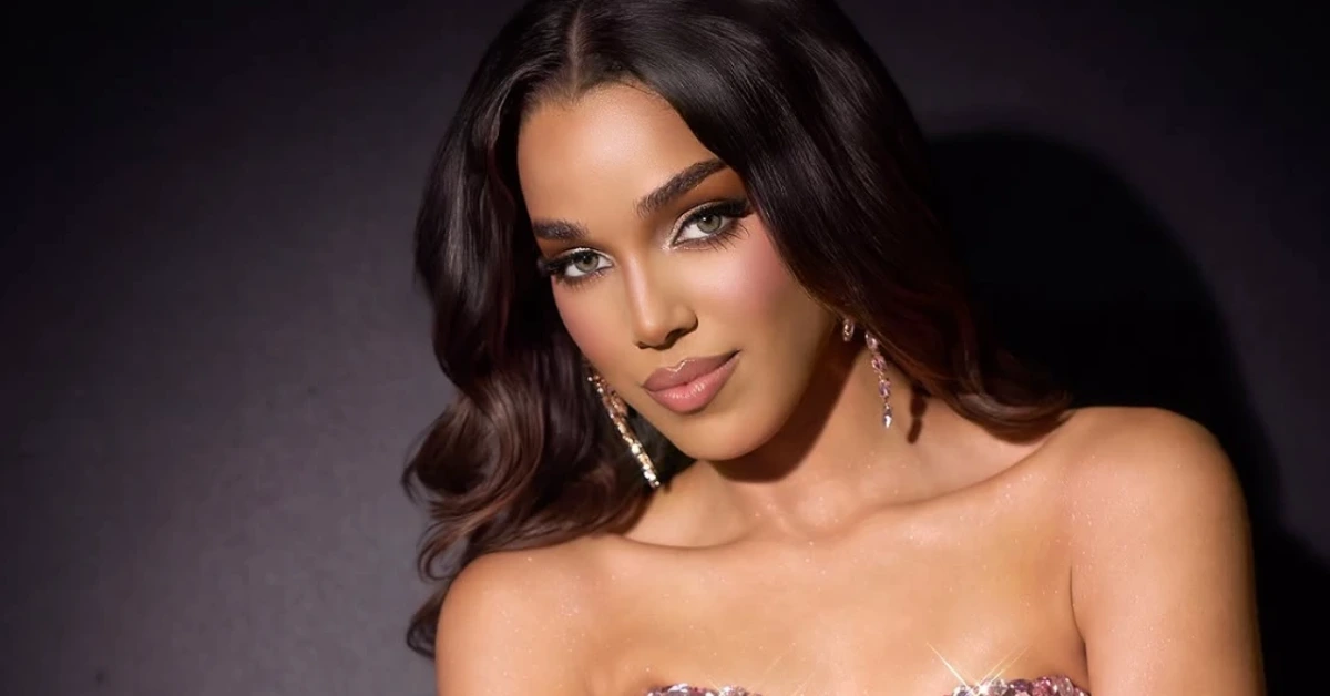 Glamorous portrait of a woman with dark hair, diamond earrings, and a shimmery strapless top against a dark backdrop.
