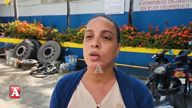 Woman speaks to the camera in an outdoor workshop area with tires and bikes in the background.