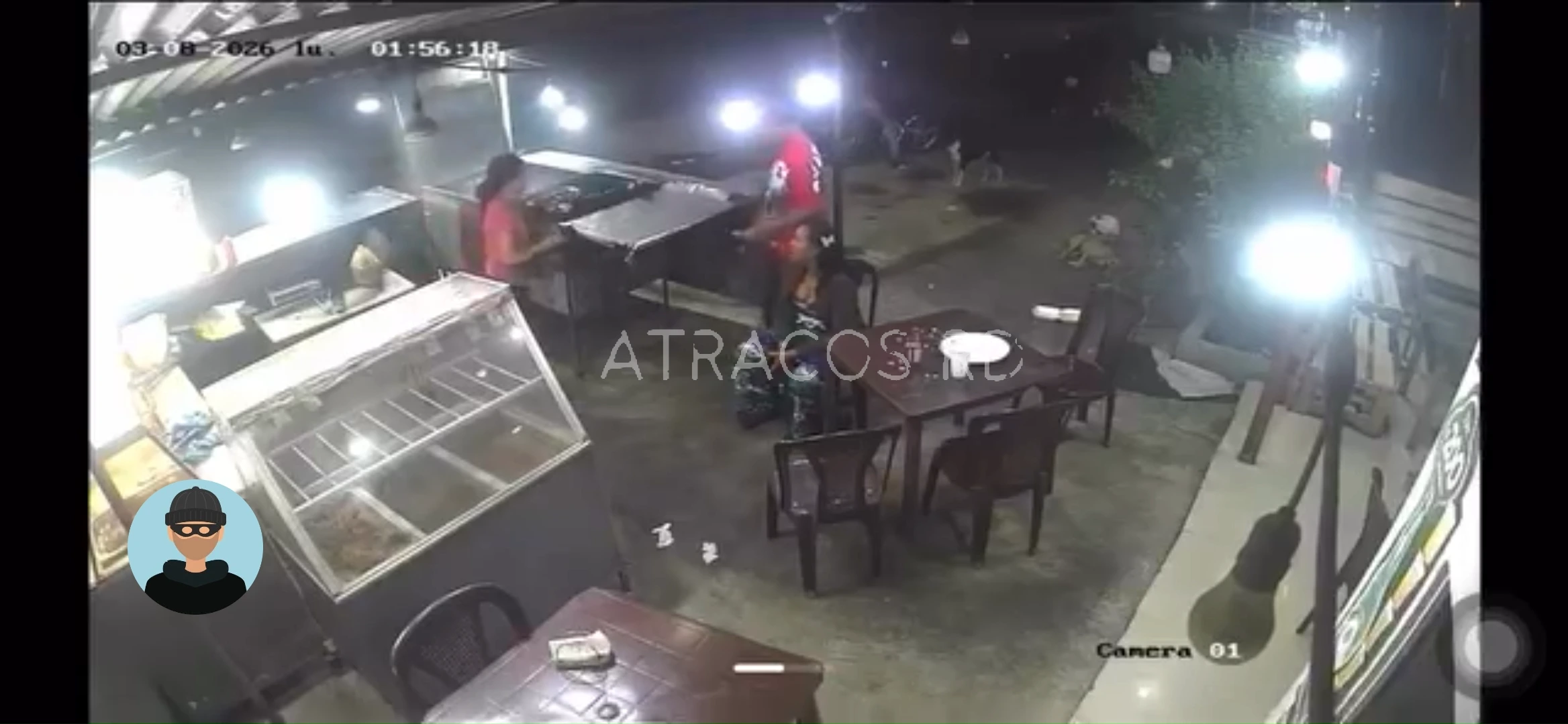Nighttime street cafe scene with two people near a counter and outdoor tables, CCTV timestamp visible in top left.