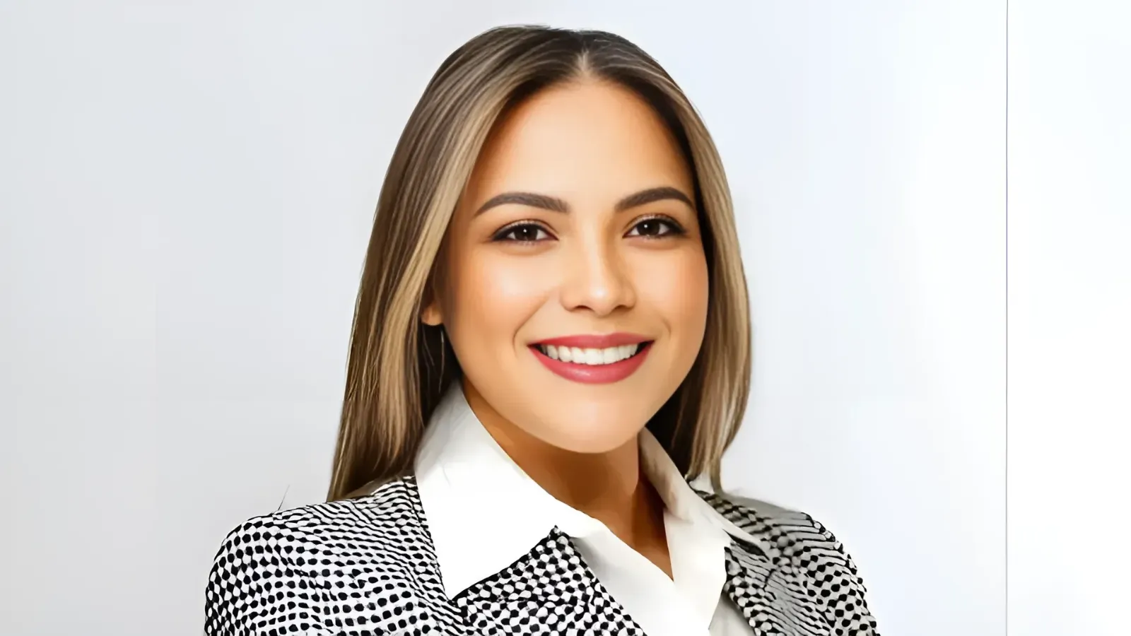 Smiling woman in a patterned blazer and white shirt, facing the camera for a professional headshot.