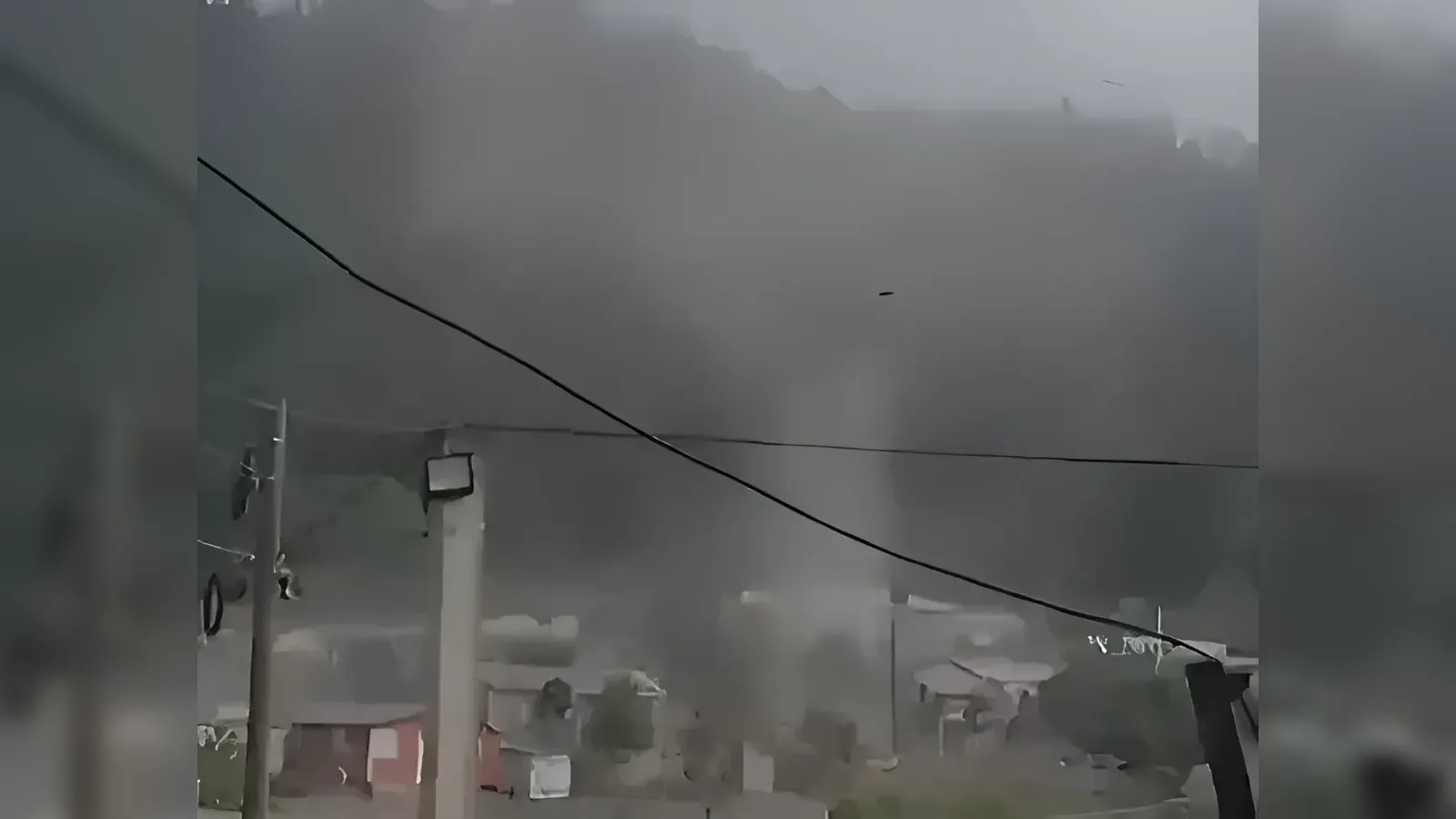Stormy urban scene with dark clouds, dust in the air, and power lines in the foreground.