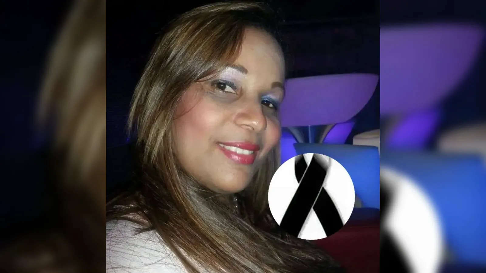 Smiling woman with long brown hair and red lipstick in a dimly lit car, purple background, with a black memorial ribbon overlay.