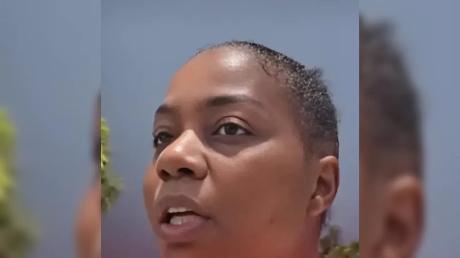 Close-up of a person speaking outdoors against a blue, clear sky.