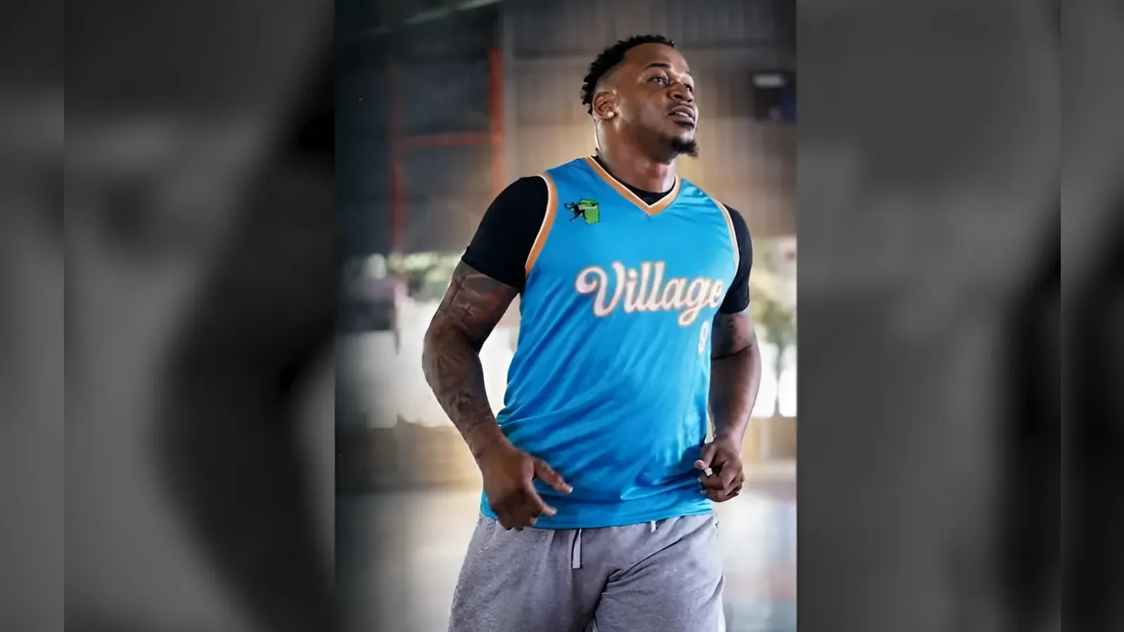 Athletic man in a blue sleeveless jersey with orange trim posing with hands on hips.