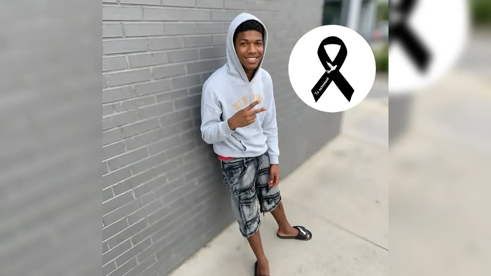Young man in a gray hoodie and patterned shorts leaning against a brick wall, smiling and flashing a peace sign, with a black awareness ribbon logo overlay.