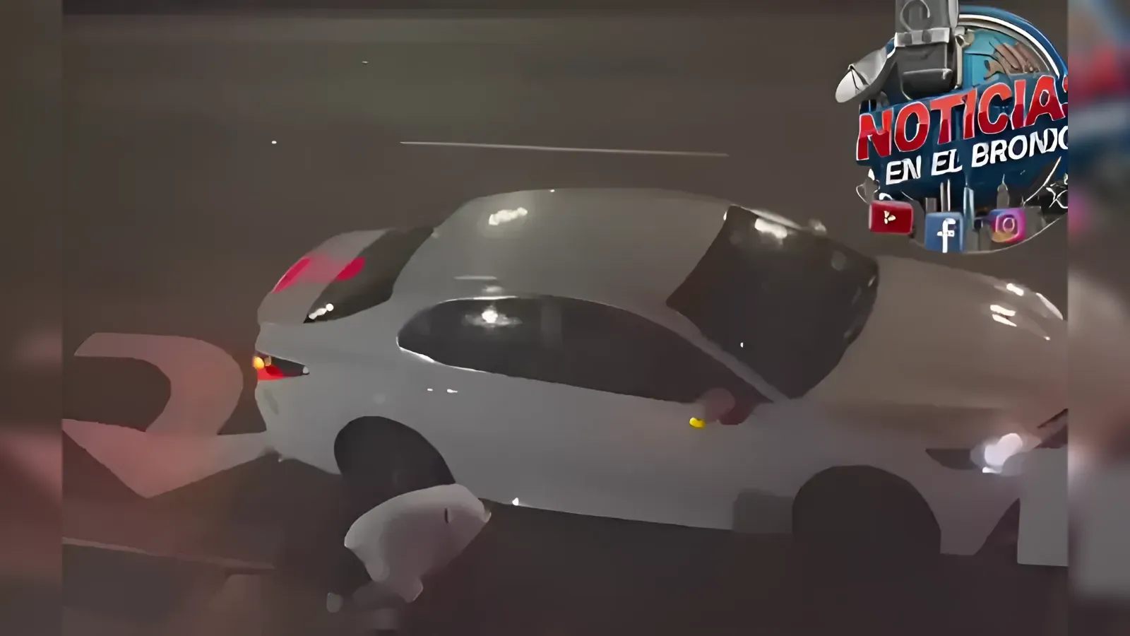 White hatchback car at night with a person on the ground nearby, suggesting a crash scene (news context).