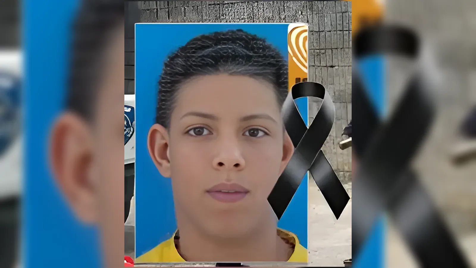 Portrait of a young man with short black hair, blue background, wearing a yellow shirt; black mourning ribbon overlapped on the right side.