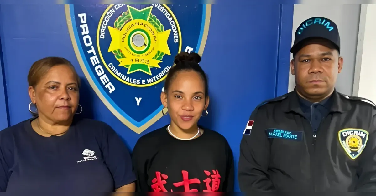 Three people stand side by side in front of a blue police emblem wall: two civilians on the left and a uniformed officer on the right.