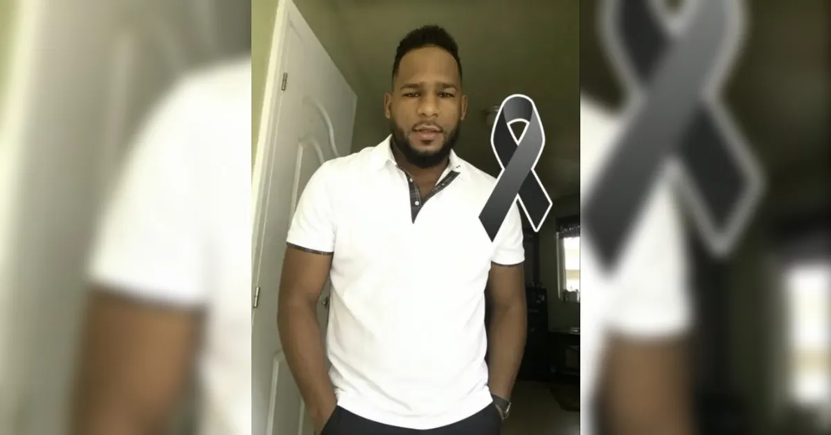 Man in a white polo shirt stands indoors with hands in pockets; a gray awareness ribbon overlays his chest area.
