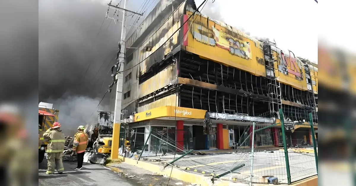 Firefighters in gear stand near a two-story commercial building with a yellow Whirlpool sign as thick black smoke pours from the upper floors.